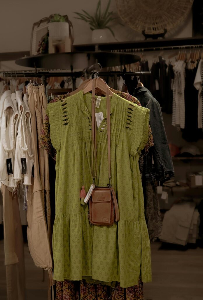 Stylish green bohemian dress on display with accessories in an indoor boutique setting.